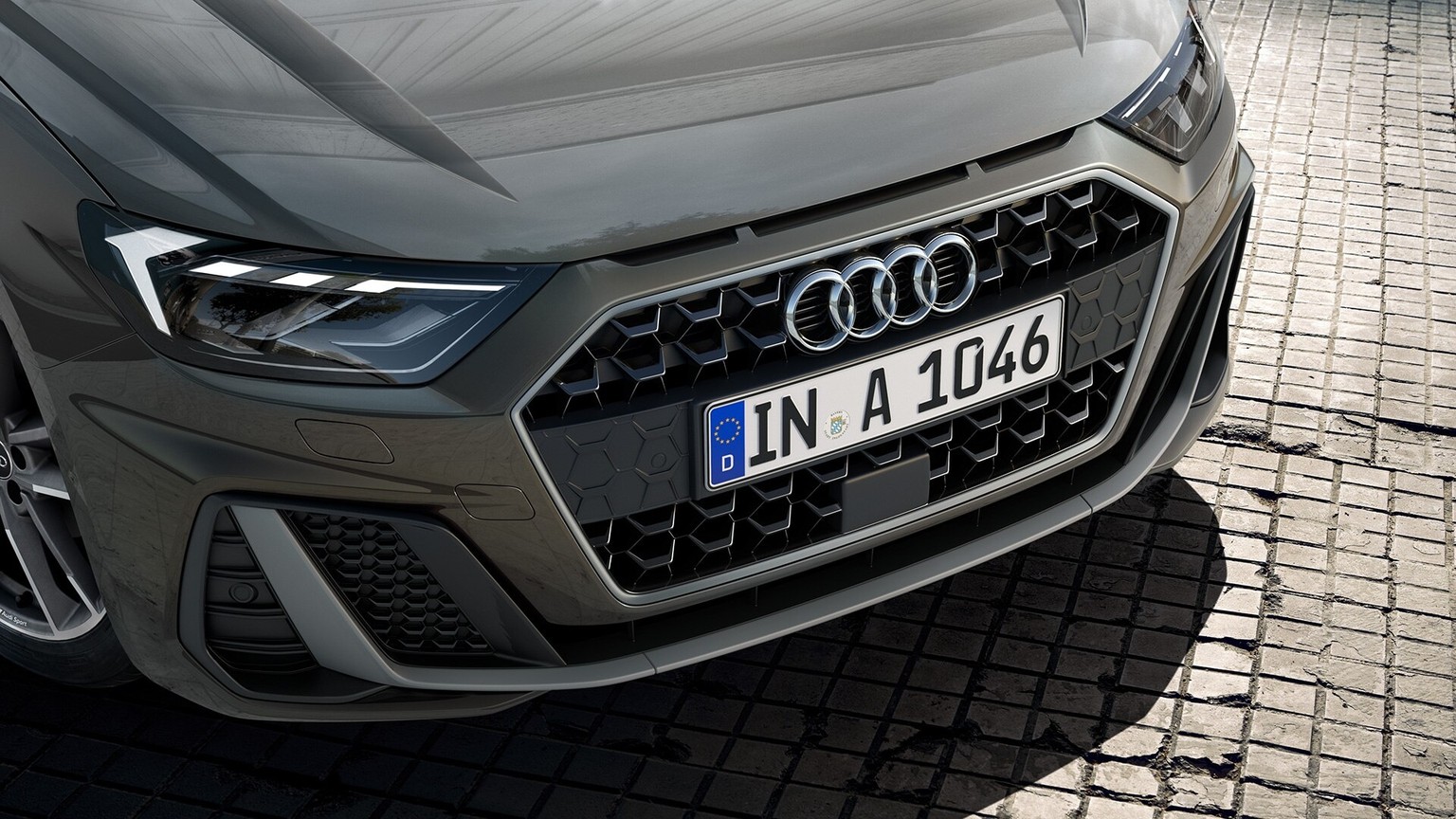 The wide track and short overhangs of the all-new Audi A1 Sportback provide for a taut, sporty look. The wide, low-placed Singleframe grille and the implied side air inlets dominate the distinctive front. Overseas model with optional equipment shown.